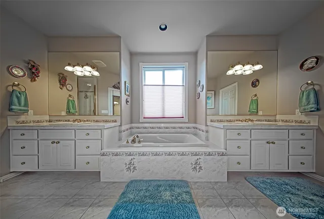 a bathroom with a granite countertop sink a large mirror and a bathtub
