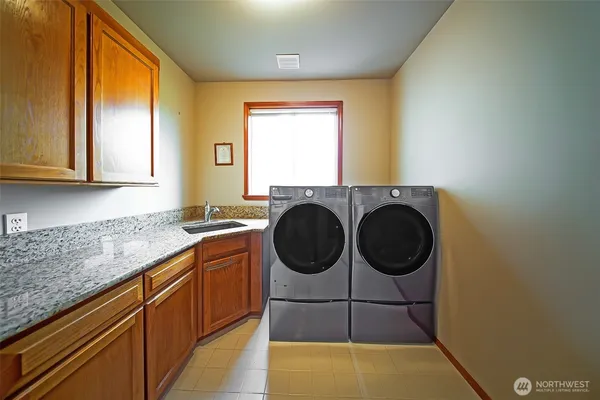 a bathroom with a granite countertop sink and a washing machine