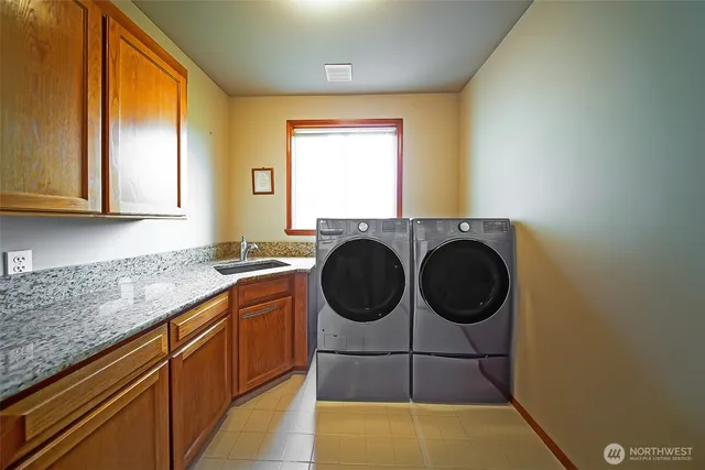 a bathroom with a granite countertop sink and a washing machine