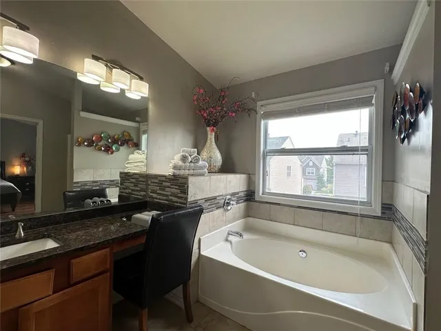 a spacious bathroom with a bathtub a sink a large mirror and a window