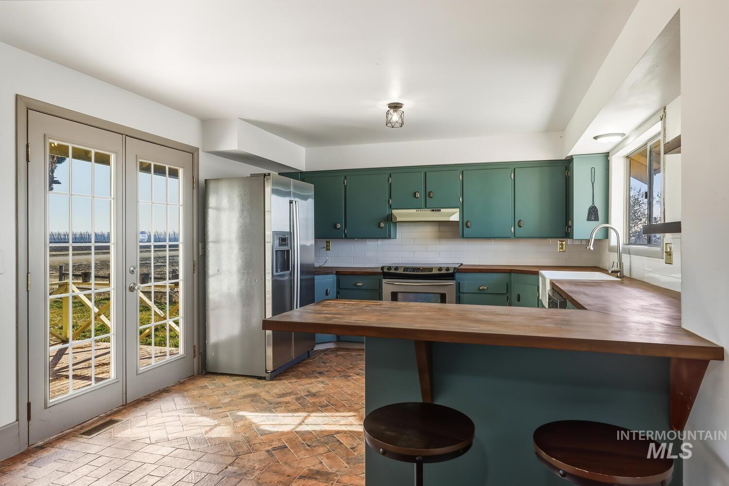 22573 Travis Road Wilder, ID 83676 - Photo 13 of 30 Kitchen featuring stainless steel appliances, a breakfast bar area, green cabinetry, a peninsula, and butcher block countertops