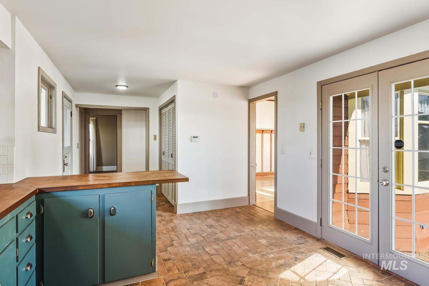 22573 Travis Road Wilder, ID 83676 - Photo 14 of 30 Kitchen featuring green cabinetry, butcher block counters, french doors, brick patterned flooring, and a peninsula
