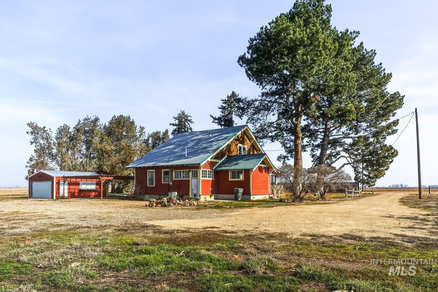 22573 Travis Road Wilder, ID 83676 - Photo 29 of 30 View of front of house with an outbuilding, a metal roof, a garage, a front lawn, and dirt driveway