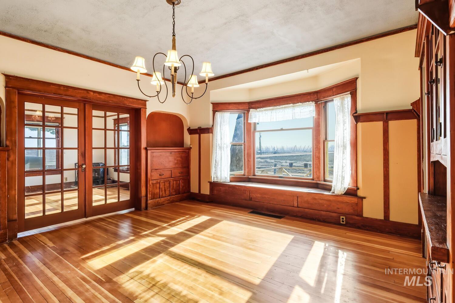 22573 Travis Road Wilder, ID 83676 - Photo 10 of 30 Spare room with french doors, light wood-style floors, and hanging lights
