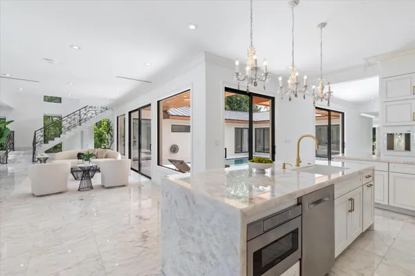 a kitchen with stainless steel appliances a stove a white cabinets and a chandelier