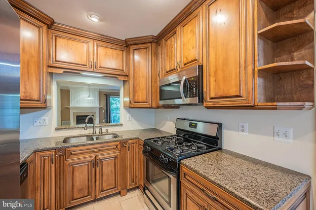 a view of an empty room with wooden floor fireplace and a window