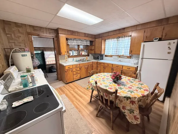 a kitchen with stainless steel appliances granite countertop a stove a refrigerator a sink dishwasher a dining table and chairs with wooden floor