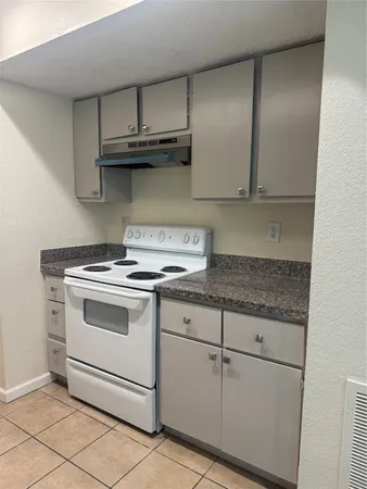 a kitchen with granite countertop white cabinets and a stove