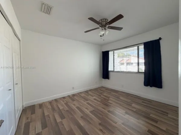 a view of empty room with wooden floor and fan