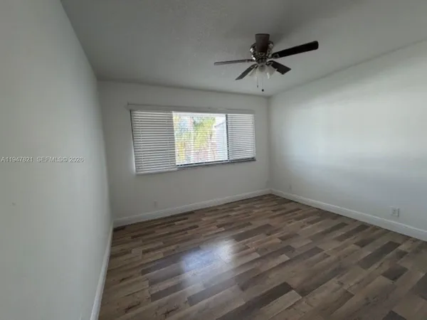 an empty room with wooden floor fan and windows