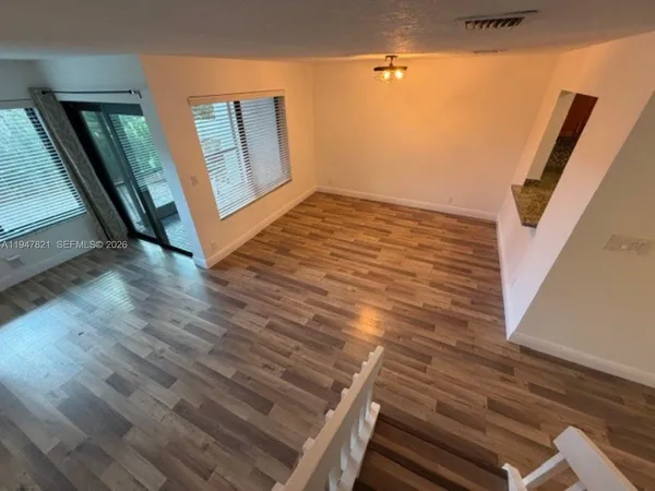 a view of an empty room with wooden floor and a window