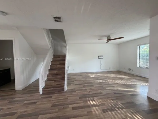 a view of empty room with wooden floor and fan