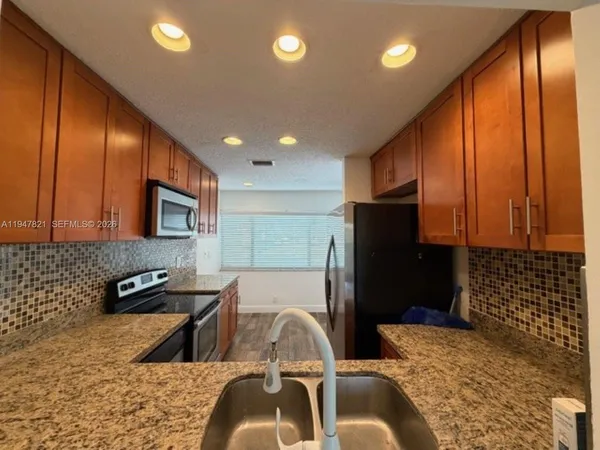 a kitchen with stainless steel appliances granite countertop a refrigerator and a sink