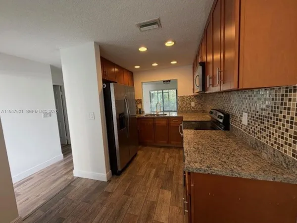 a kitchen with granite countertop stainless steel appliances a refrigerator and a counter top space