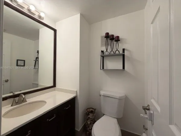 a bathroom with a sink vanity mirror and toilet