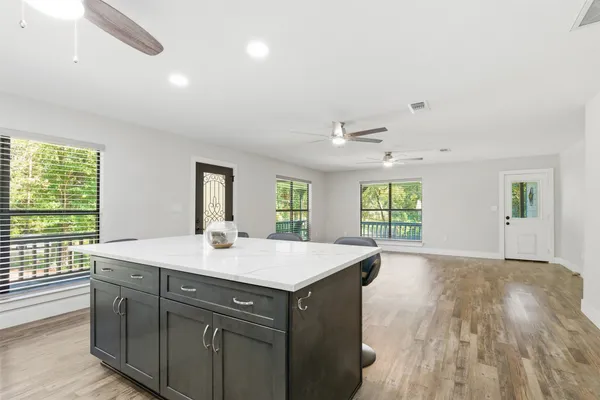 a hall with kitchen island a stove a wooden floors and a large window