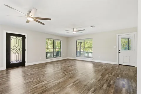 a view of an empty room with wooden floor and a window