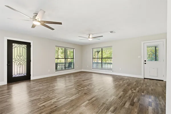 a view of an empty room with wooden floor and a window