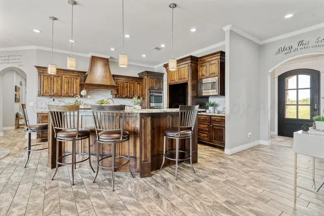 a kitchen with stainless steel appliances kitchen island granite countertop a table chairs and a refrigerator