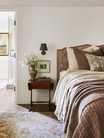 a bed sitting in a bedroom next to a window with potted plants