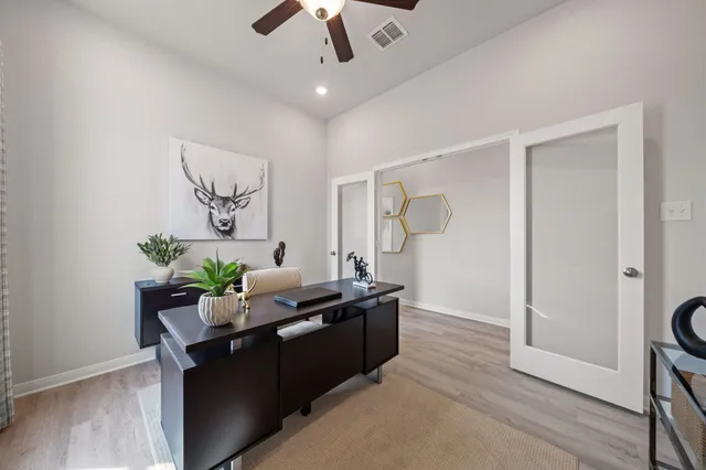 a dining room with wooden floor a chandelier fan a wooden table and chairs