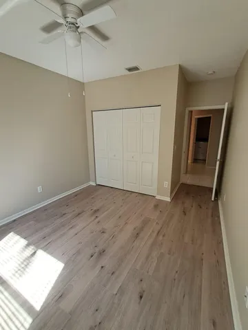 an empty room with wooden floor fan and windows