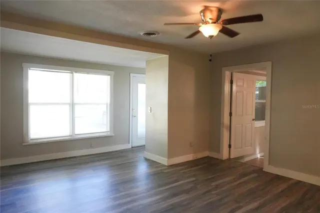 a view of empty room with wooden floor and fan