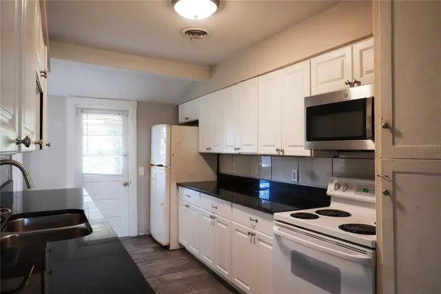 a kitchen with stainless steel appliances a stove a microwave and white cabinets