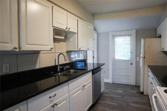 a kitchen with granite countertop a sink stove and cabinets