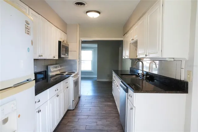 a kitchen with granite countertop a sink a stove and cabinets