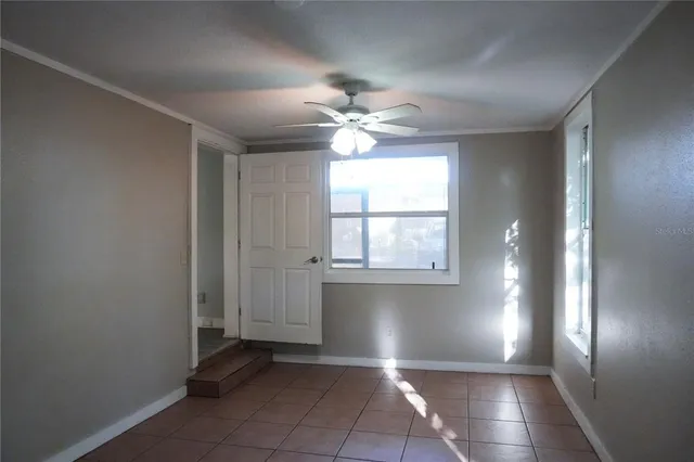an empty room with windows and fan