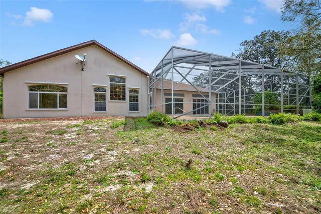 an empty room with chandelier fan and windows
