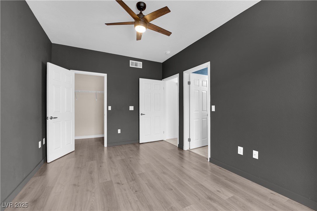 10550 West Alexander Road, Unit 2079 Las Vegas, NV 89129 - Photo 19 of 40 Unfurnished bedroom featuring light wood-style floors, baseboards, and a walk in closet