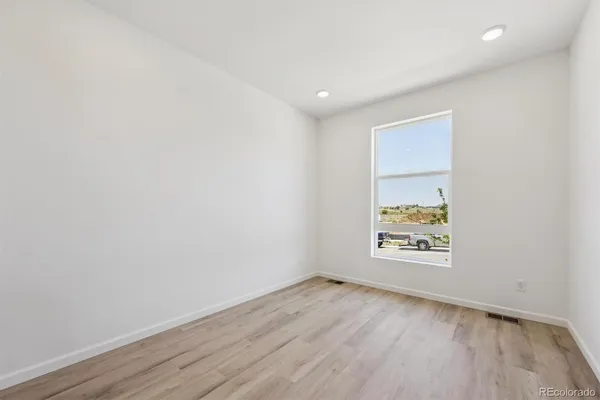 an empty room with wooden floor and windows