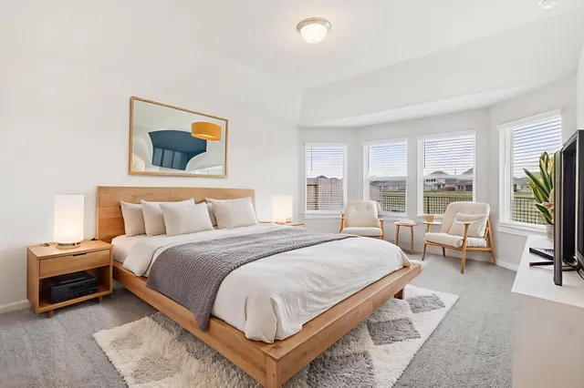 a bedroom with a bed a large window and a flat screen tv