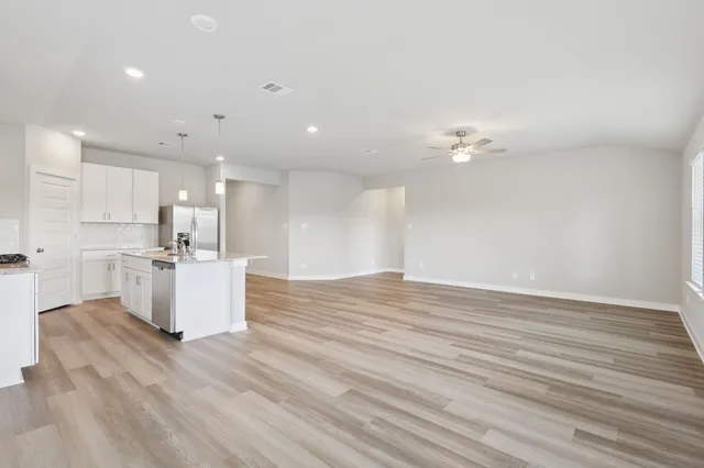 a view of kitchen with kitchen island stainless steel appliances wooden floor cabinets oven and a sink with granite countertops