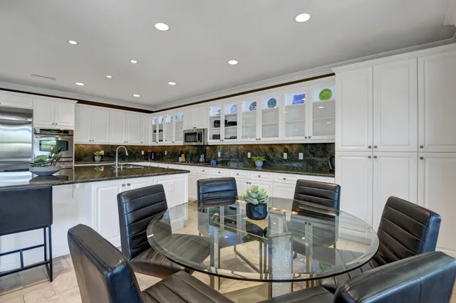 a kitchen with stainless steel appliances granite countertop a stove a refrigerator a kitchen island a table and chairs