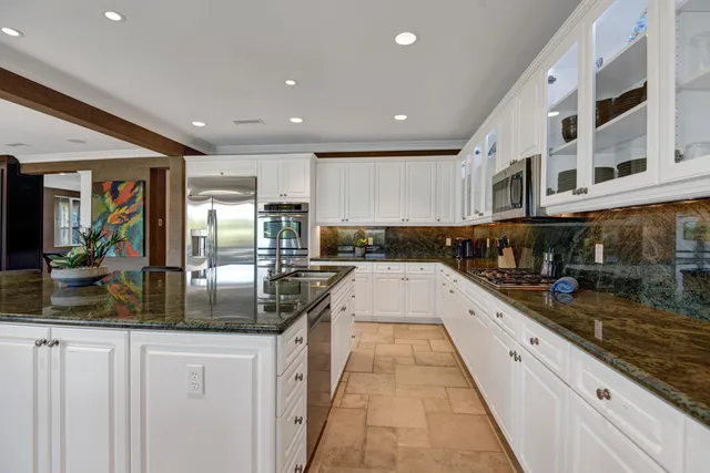 a large kitchen with stainless steel appliances granite countertop a large counter top a stove and a sink
