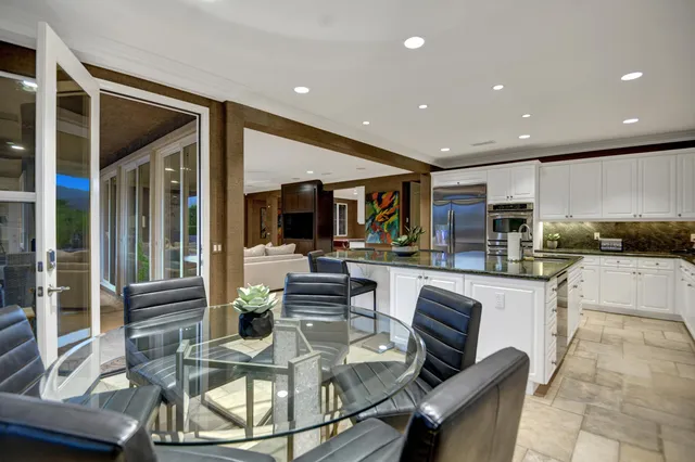 a living room with stainless steel appliances furniture a rug and a kitchen view