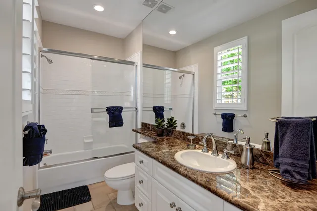 a bathroom with a sink a toilet a mirror and shower