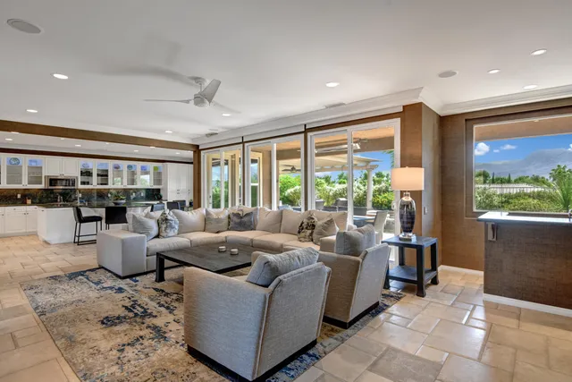 a living room with furniture large windows and view of kitchen