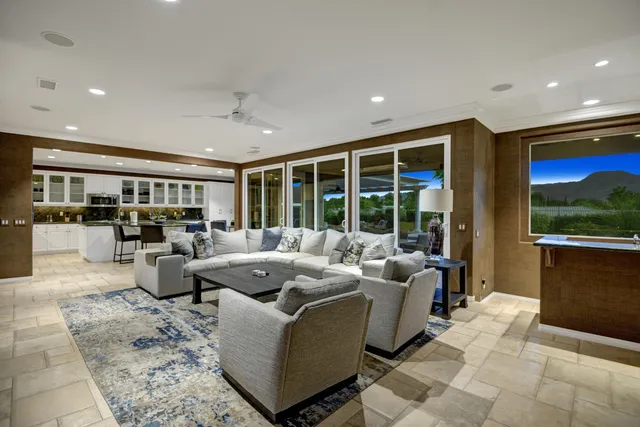 a living room with furniture large window and kitchen view
