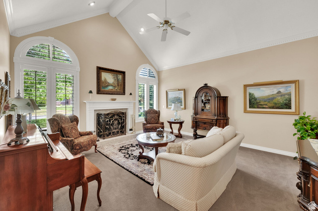 7740 Keswick Road Sandy, UT 84093 - Photo 13 of 74 Vaulted ceiling living area featuring a central fireplace with decorative screen, arched windows with plantation shutters, recessed lighting, and a ceiling fan