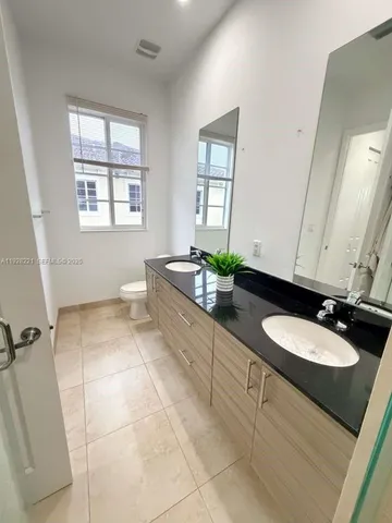 a bathroom with a granite countertop sink a toilet and mirror