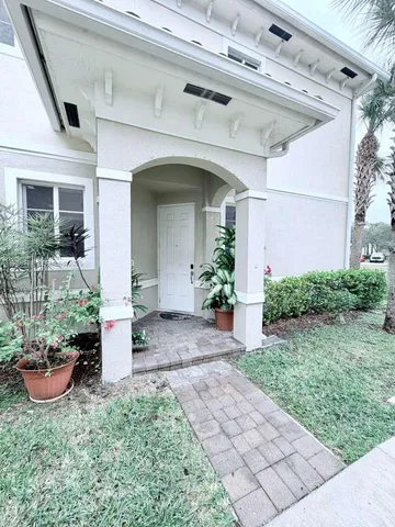 a view of a house with potted plants and a bench
