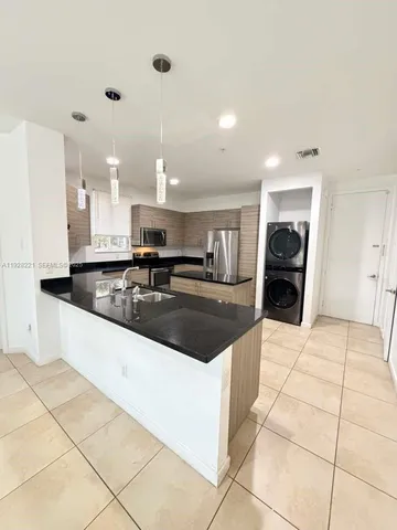 a large kitchen with kitchen island granite countertop a sink and a stove top oven
