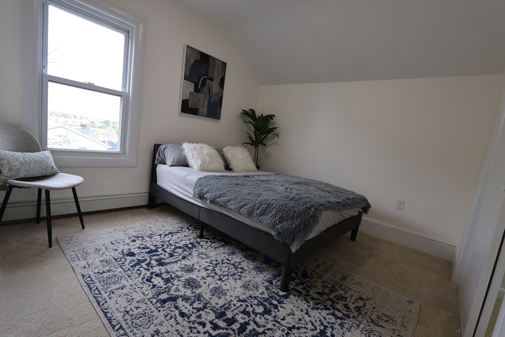 331 Proctor Avenue Revere, MA 02151 - Photo 17 of 29 a bedroom with a bed and a chair next to a window