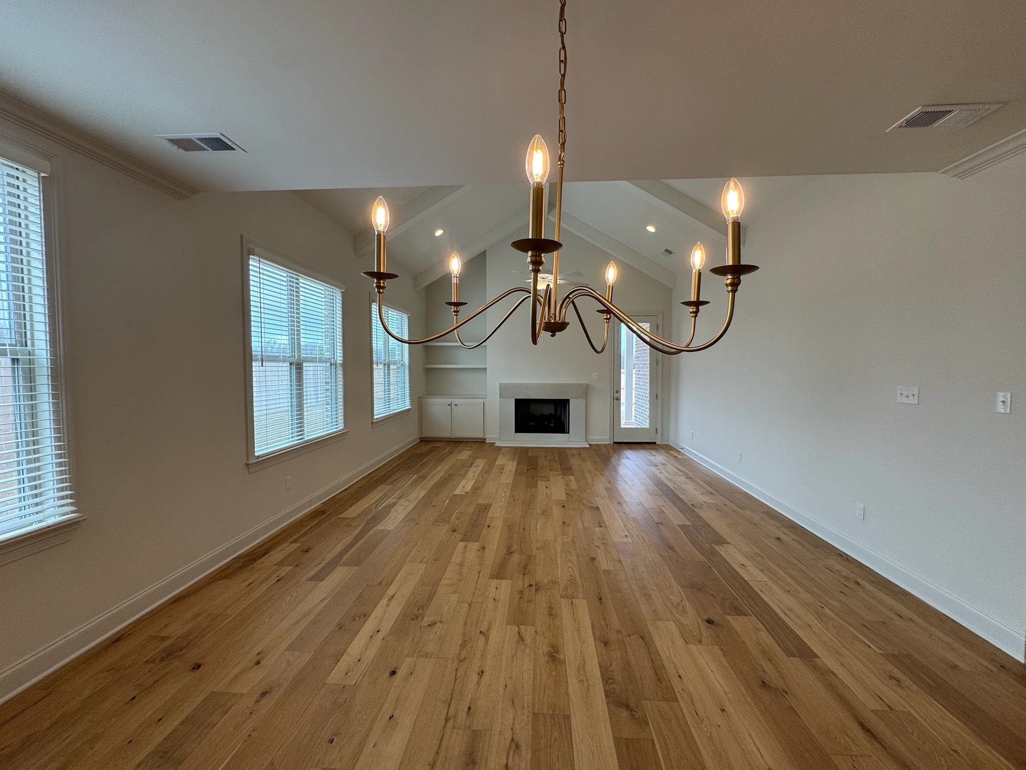 11512 Sunsparkler Way Collierville, TN 38017 - Photo 9 of 40 Unfurnished living room with lofted ceiling, light wood-type flooring, a chandelier, and a fireplace