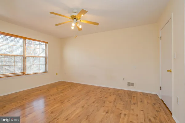 an empty room with a chandelier fan and windows