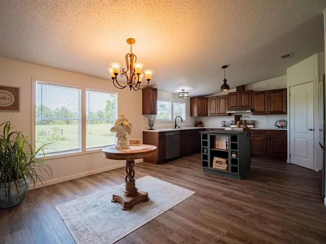 a kitchen with kitchen island granite countertop a sink cabinets and window